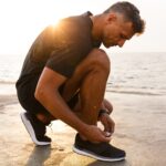 Man tying his running shoes on a beach