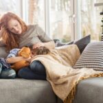 Mom comforting young son on couch with the Dad drinking coffee in the background