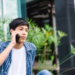 Teenage boy making a phone call sitting outside of a building